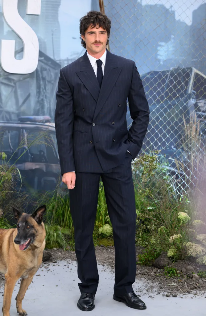 Jacob Elordi in a pinstripe suit, with a dog next to him, at 