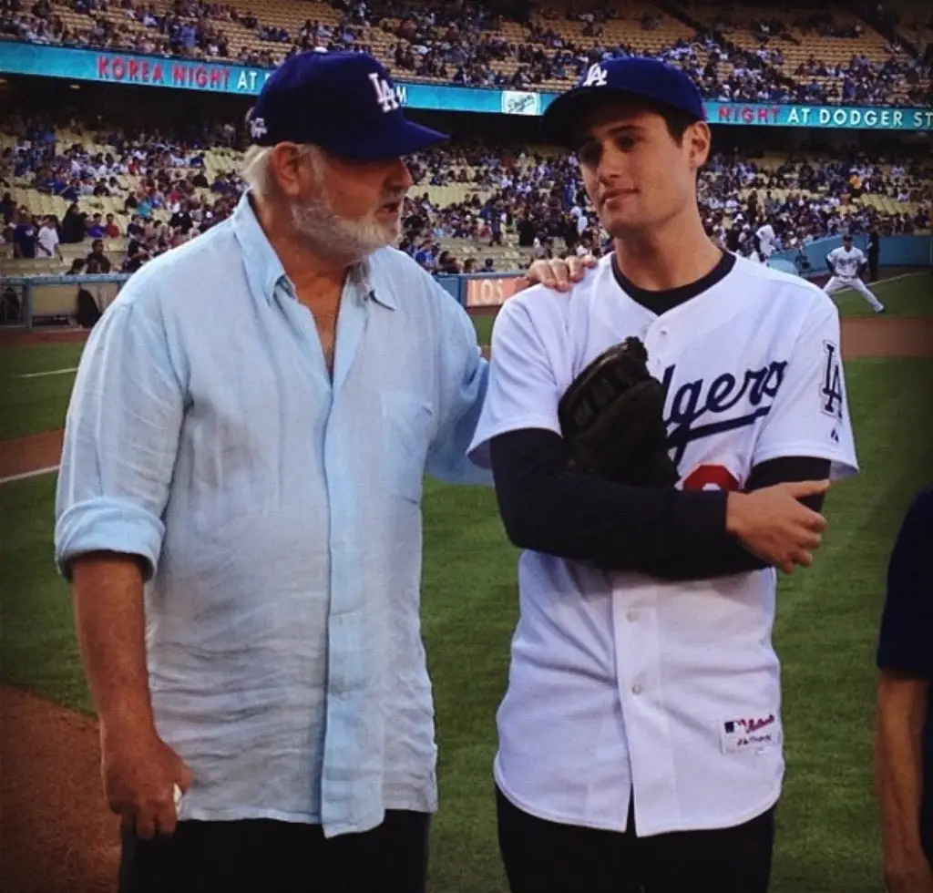 Rob and Jake Reiner posing together at a baseball game.