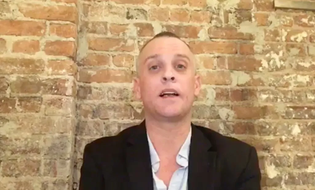 James Vituscka, a reporter, speaking against a brick wall.