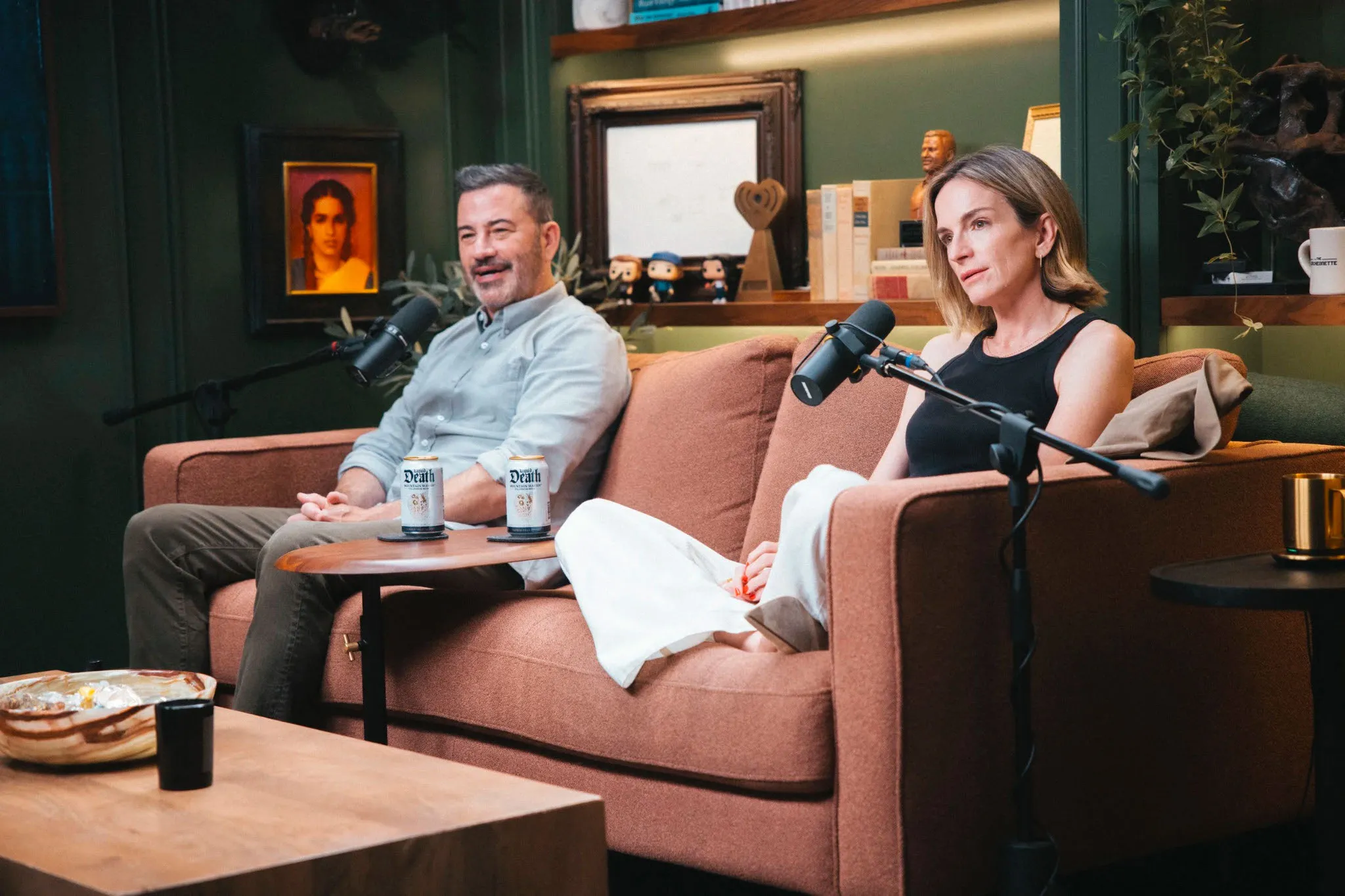 Jimmy Kimmel and Molly McNearney sitting on a couch for a podcast interview.