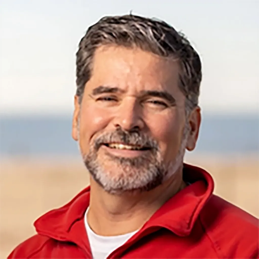 Joshua Kohut, 51, smiling in a red jacket.