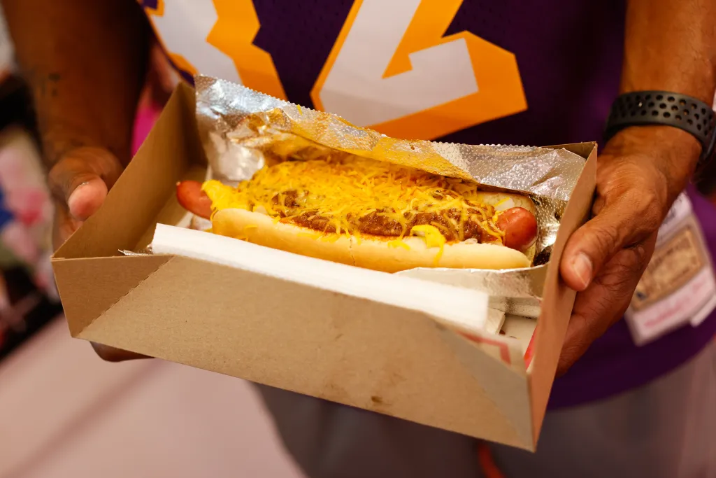 Joe Douglas holding a free chili dog in a cardboard tray at Pink's Hot Dog.