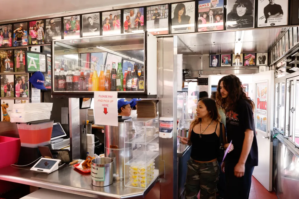 Customers wait in line at Pink's Hot Dog, with celebrity photos on the walls.