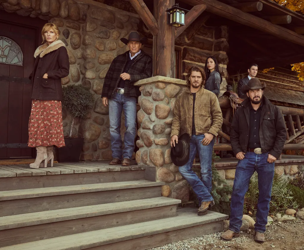 Kelly Reilly, in a brown jacket with fur trim, red patterned skirt and cream boots, Kevin Costner in a black check jacket, blue jeans and black cowboy hat,, Luke Grimes in a suede jacket and blue jeans, Kelsey Chow in a black jacket, Wes Bentley in a black jacket, Cole Hauser in a brown cowboy hat, brown jacket, black shirt and blue jeans.