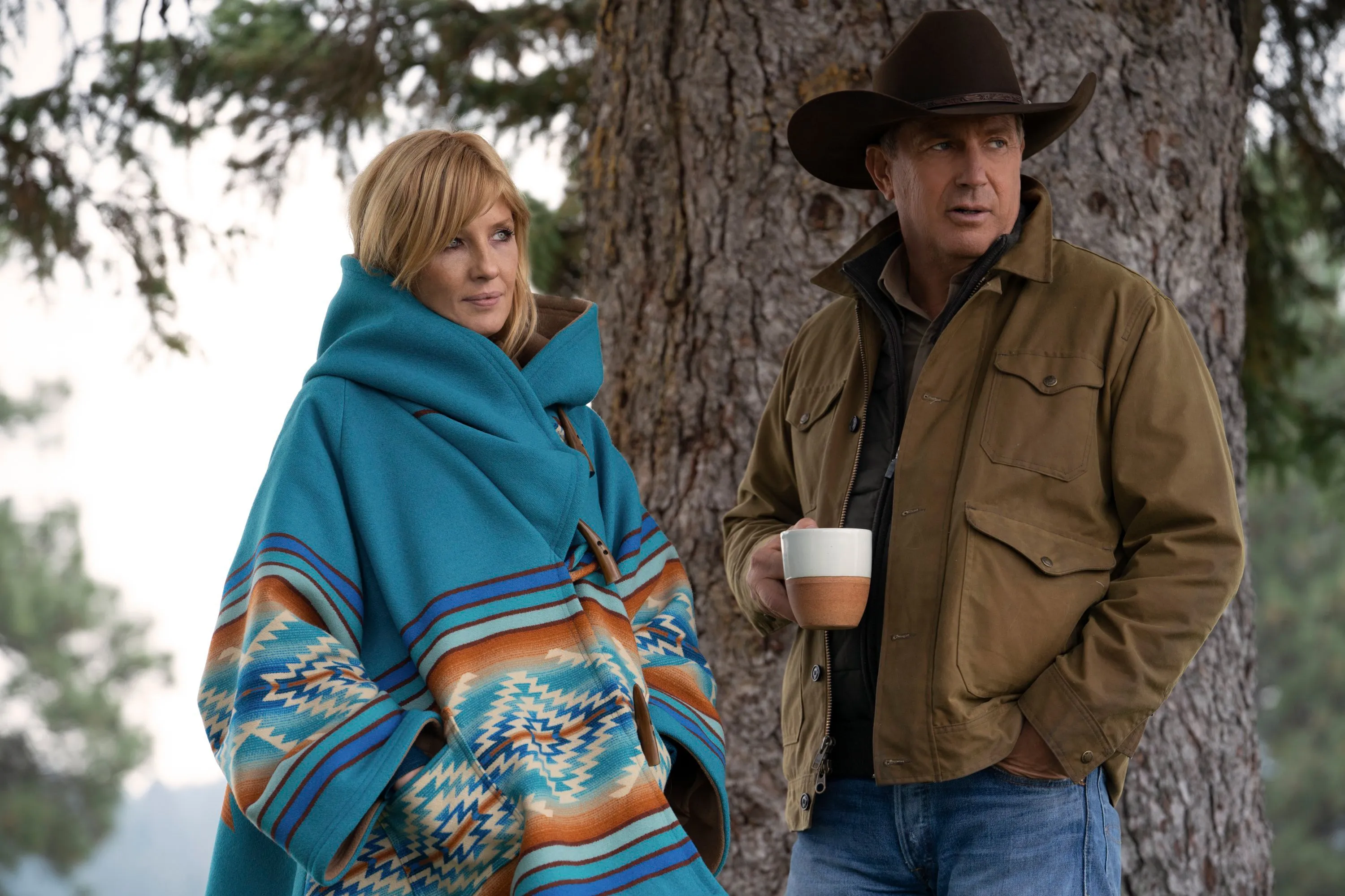 Kelly Reilly in a blue poncho and Kevin Costner in a cowboy hat on the TV series