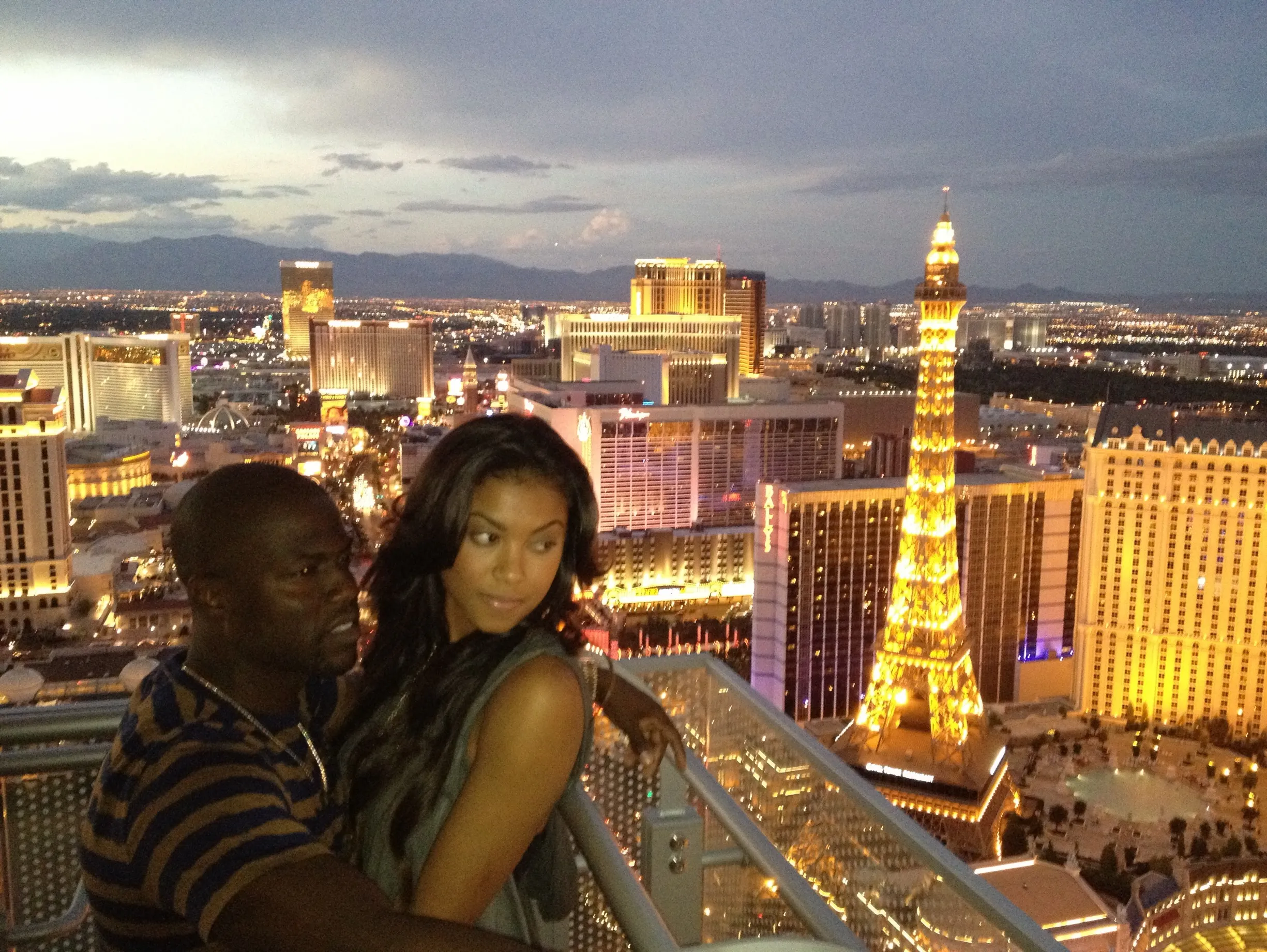 Kevin and Eniko Hart on a rooftop overlooking Las Vegas at night, with the Eiffel Tower replica visible.