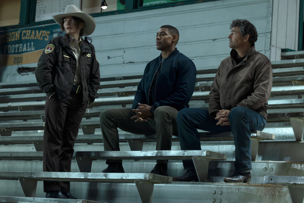 Kyle Chandler, Aaron Pierre, and another actor on bleachers in the HBO show