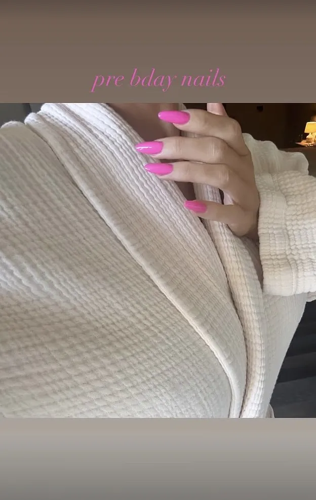 Kylie Jenner with long pink nails on a cream-colored bathrobe, with 