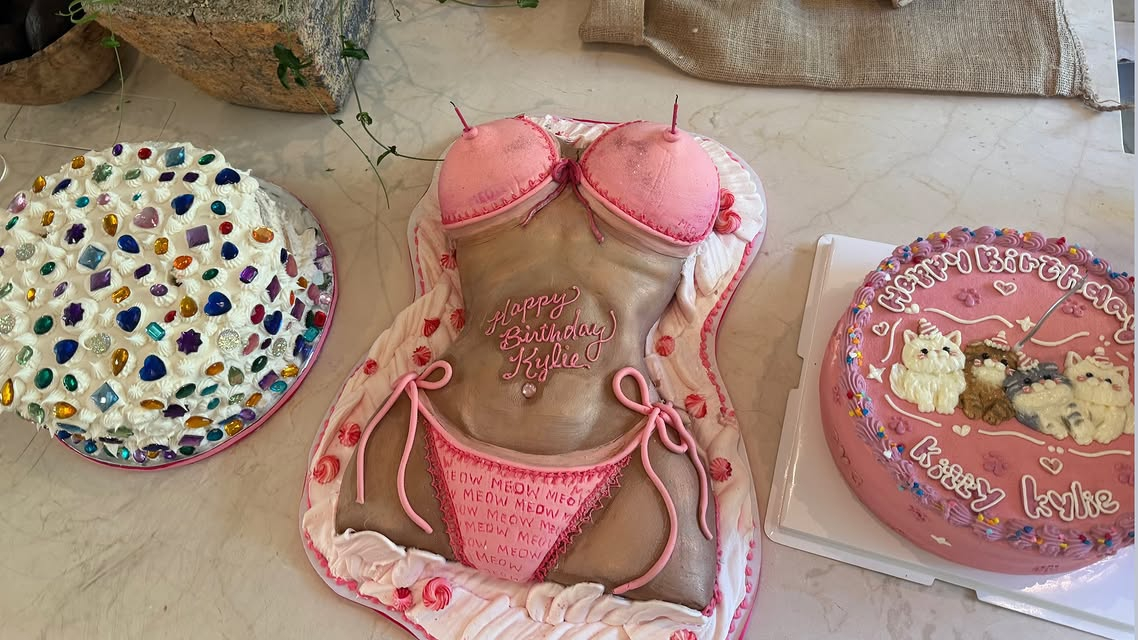 Three birthday cakes, including one shaped like a woman in a pink bikini with 