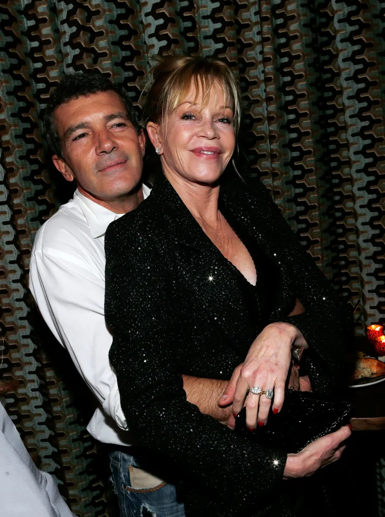 Antonio Banderas embraces Melanie Griffith from behind.