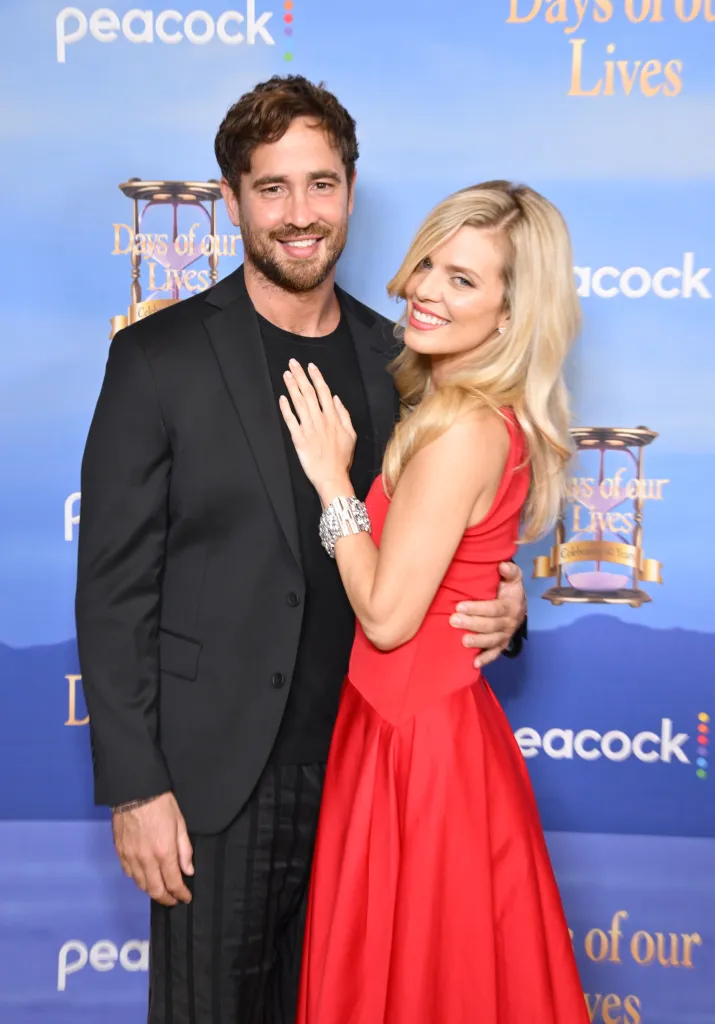 Danny Cipriani and AnnaLynne McCord smiling on a blue background at Peacock's 