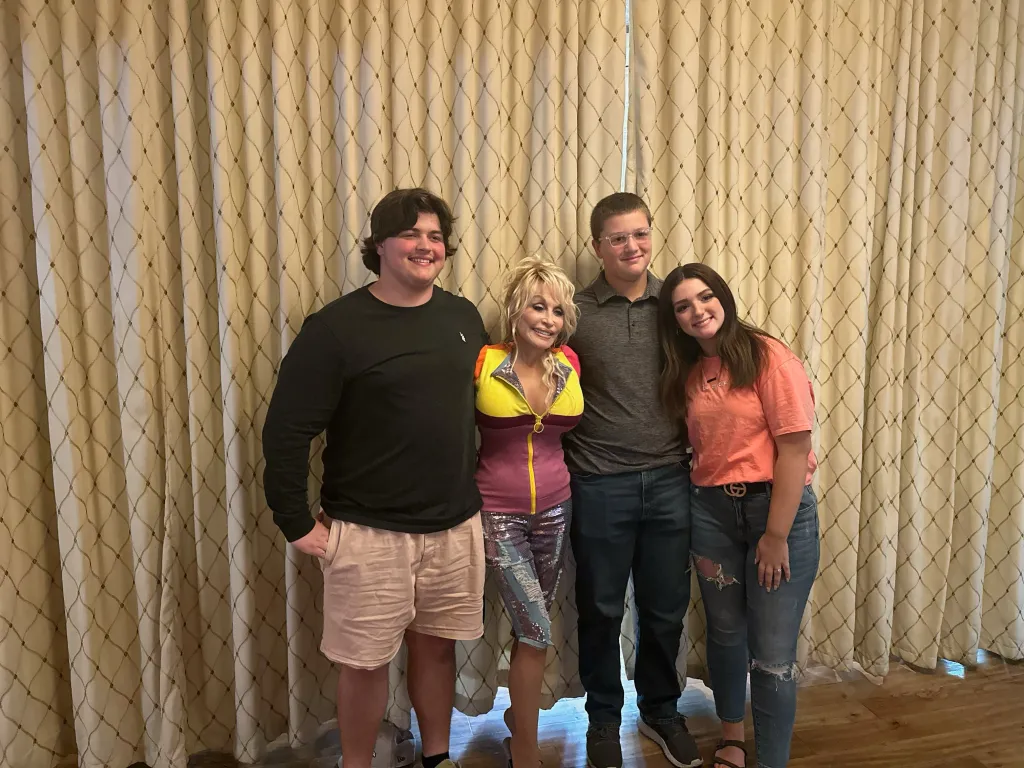 Dolly Parton posing with two young men and a young woman.