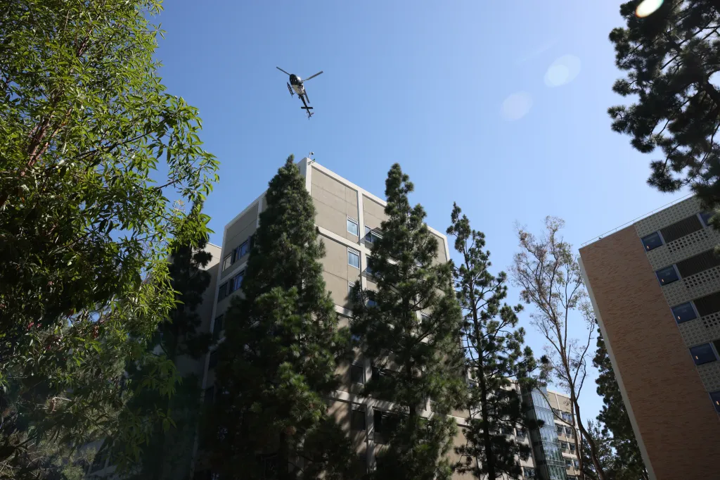 A helicopter flies above a tall building at UCLA during an LAPD SWAT drill for the Olympics.