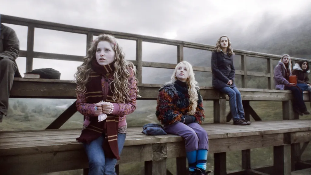 Jessie Cave, Evanna Lynch, and Emma Watson sitting on a wooden bench.