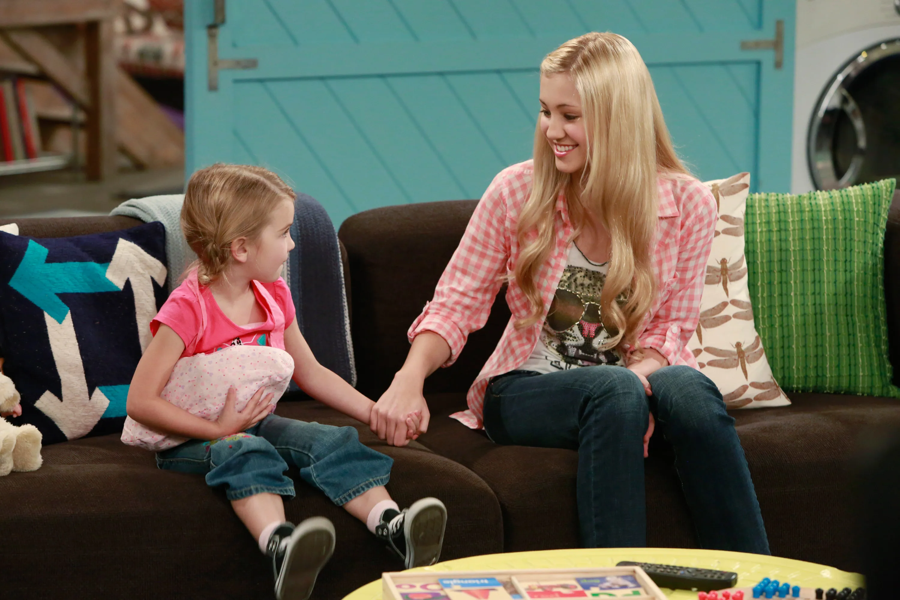 Leigh-Allyn Baker and Ava Sambora holding hands on a couch.