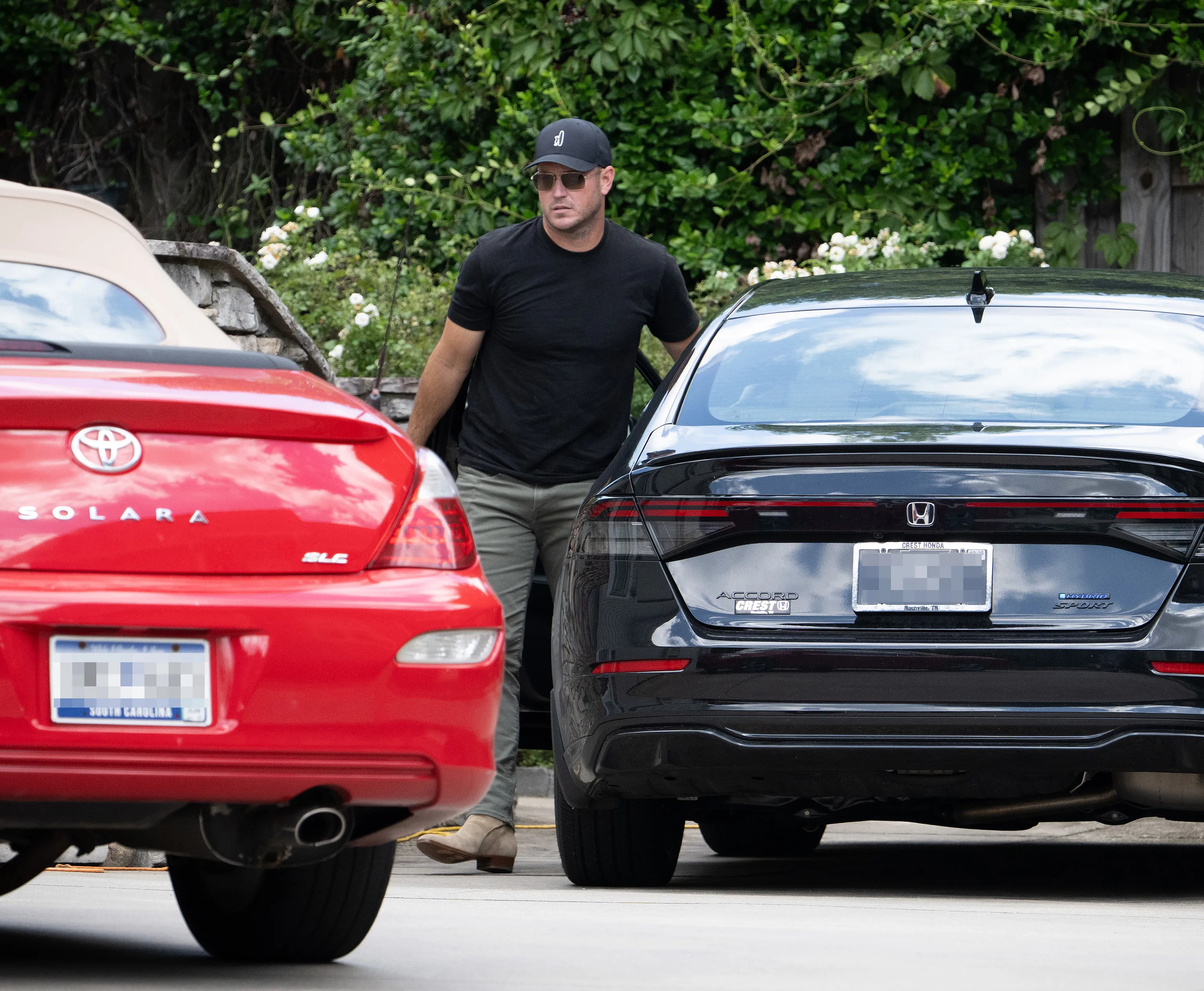 Zach Hickerson entering a black car with a red car parked nearby.