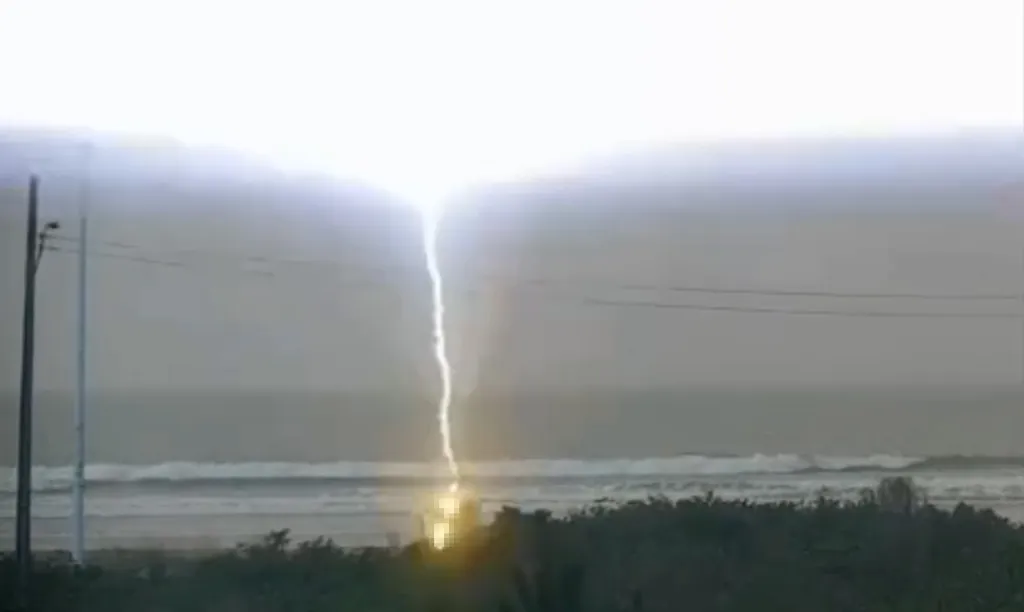 Lightning striking a beach, illuminating a woman.