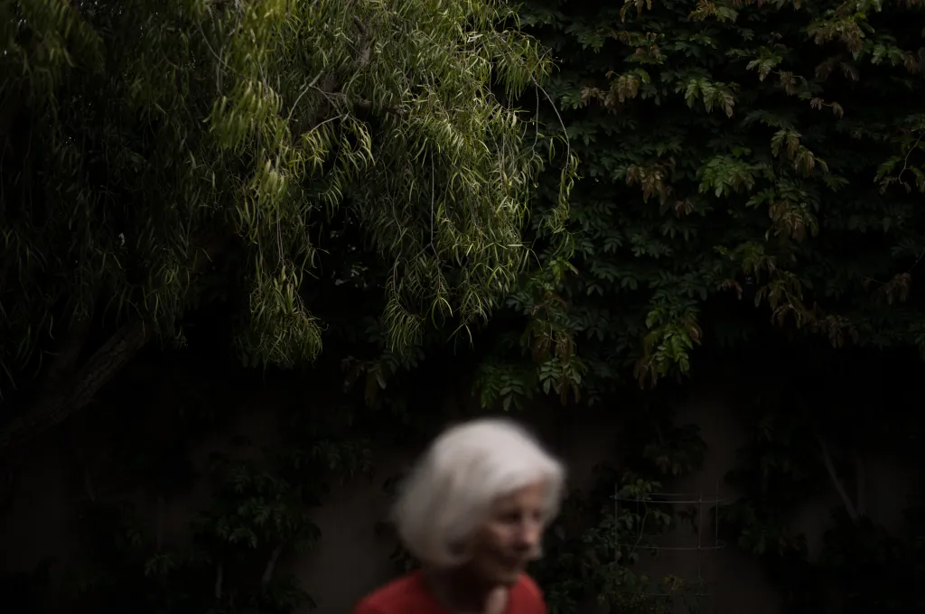 A blurry photo of Linda Henry with green foliage in the background.