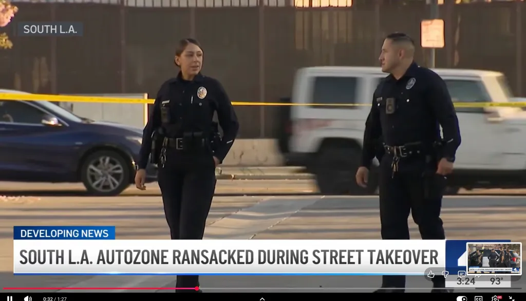 Two police officers standing on a street with yellow police tape in the background, with 