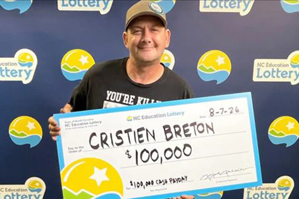 Cristien Breton holding a large check for $100,000 from the NC Education Lottery.