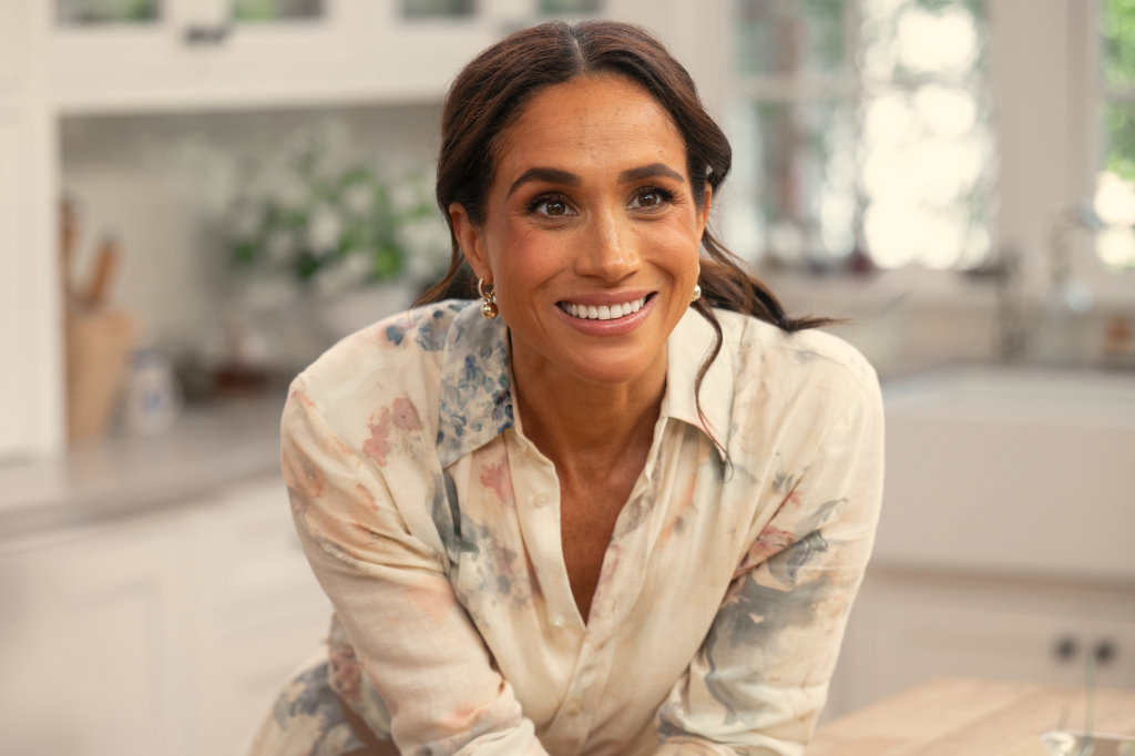 Meghan Markle smiling in a floral shirt.
