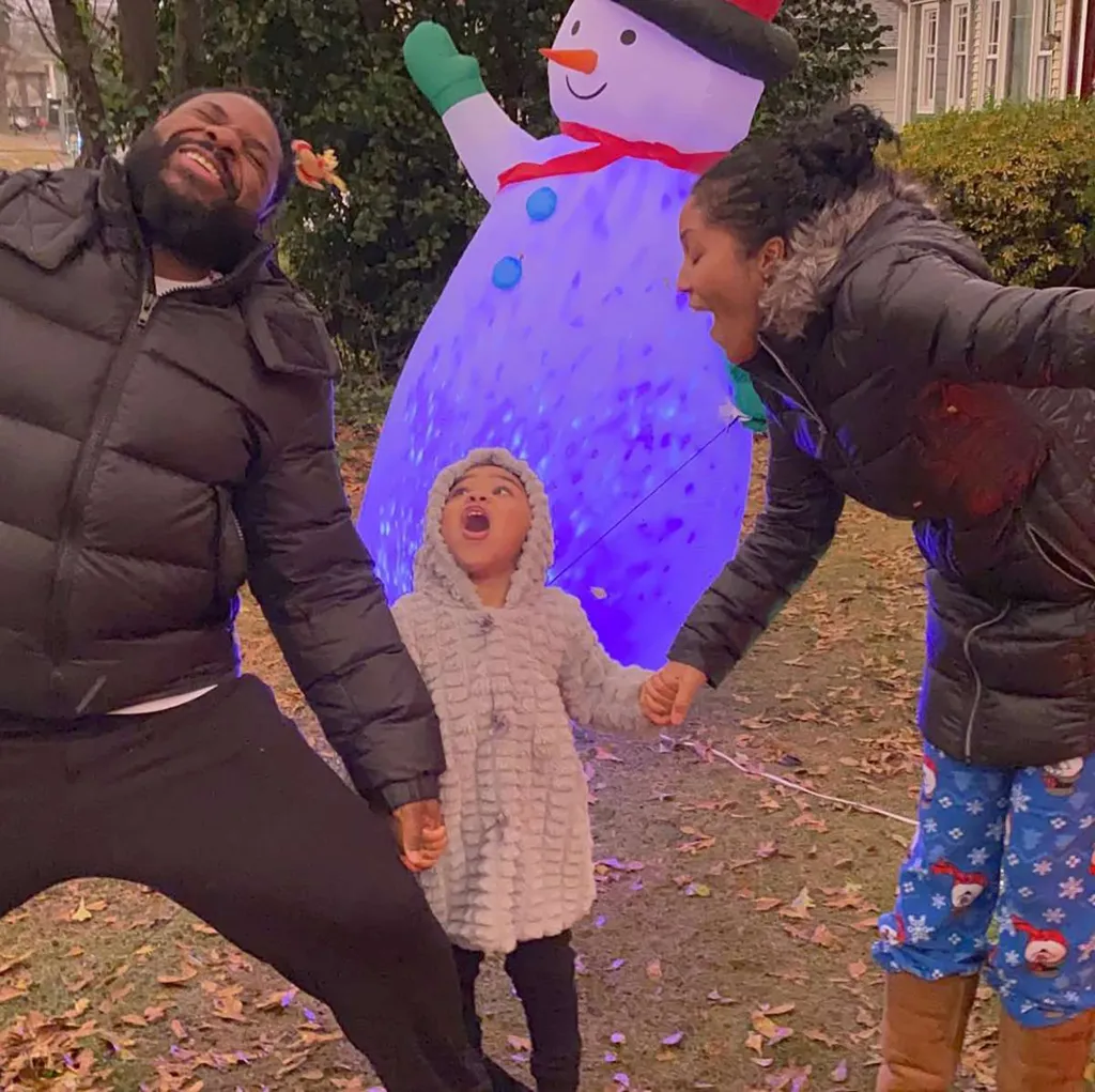 Malcolm-Jamal Warner with his wife and daughter in front of an inflatable snowman.