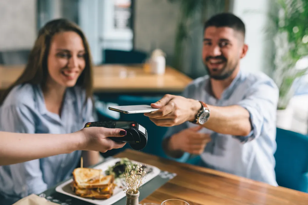 Man paying a restaurant bill contactlessly with his cellphone.