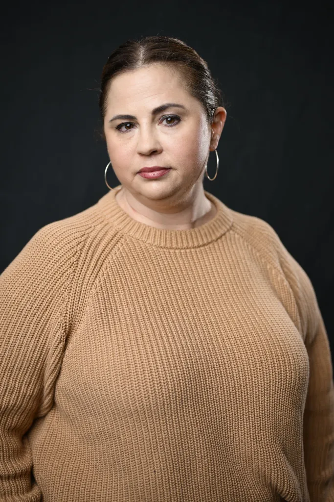 Mandy Teefey in a beige knit sweater and hoop earrings.