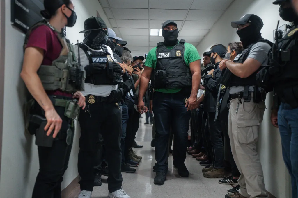 Masked federal agents wait outside an immigration courtroom in New York.