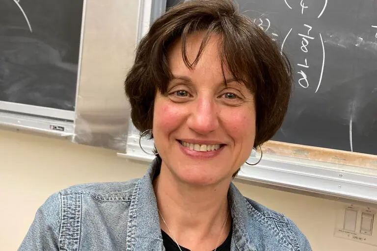 Zvezdelina Stankova, professor of mathematics at UC Berkeley, smiling in front of a blackboard.