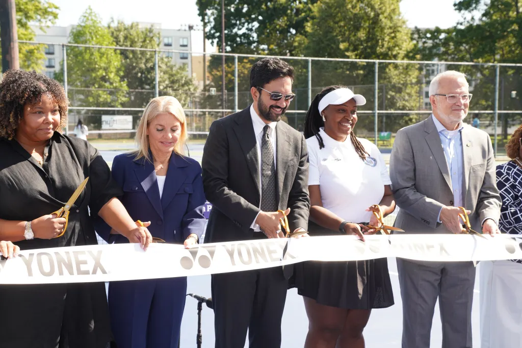 Mayor Zohran Mamdani and four other individuals cutting a Yonex ribbon at a renovated tennis court.