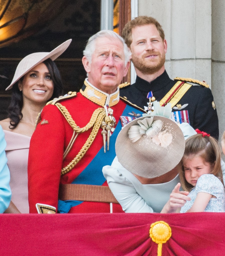 Meghan, Duchess of Sussex, in an off-shoulder pink dress and pink hat, King Charles, in a red military jacket, blue sash and medals, Prince Harry, Duke of Sussex, in a black military jacket and medals, Catherine, Duchess of Cambridge, in a blue dress and straw hat, and Princess Charlotte of Cambridge, in a blue dress, on the balcony of Buckingham Palace.