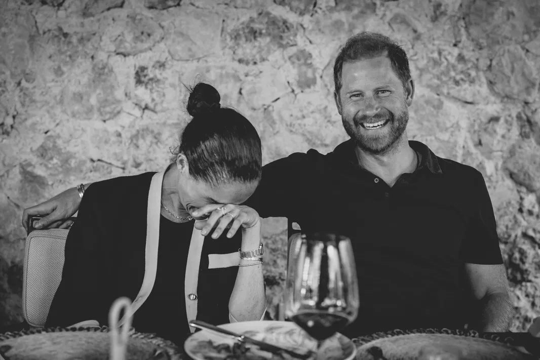Meghan Markle laughing as Prince Harry smiles brightly.