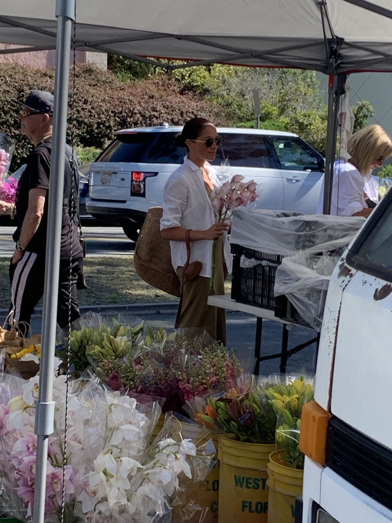 Meghan Markle holding pink orchids at a farmer's market.