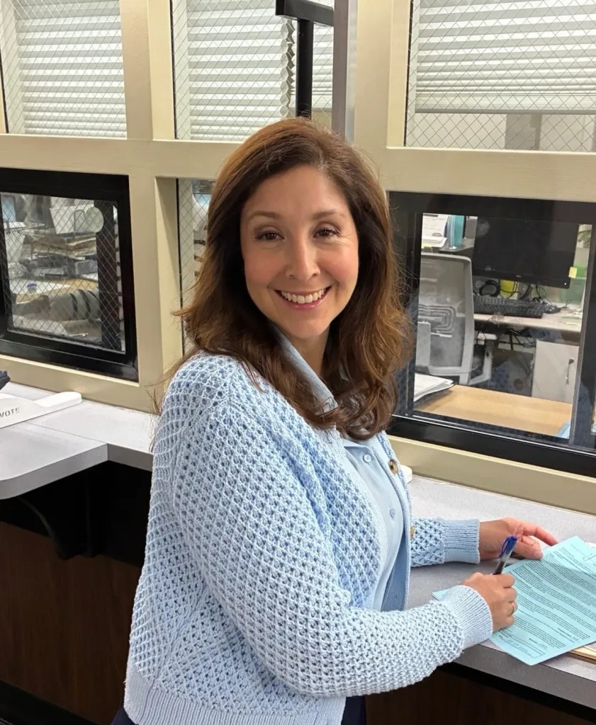 Melissa Hernandez smiling and holding a pen while looking at a document.