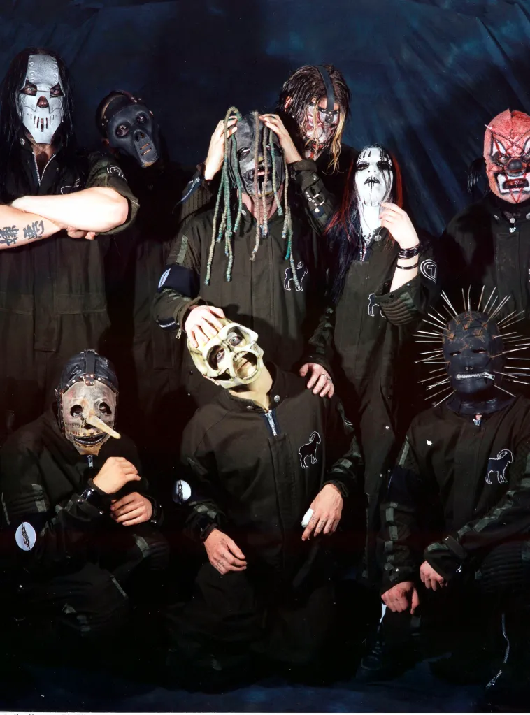 Nine members of Slipknot posing for a group photo in their masks and outfits.