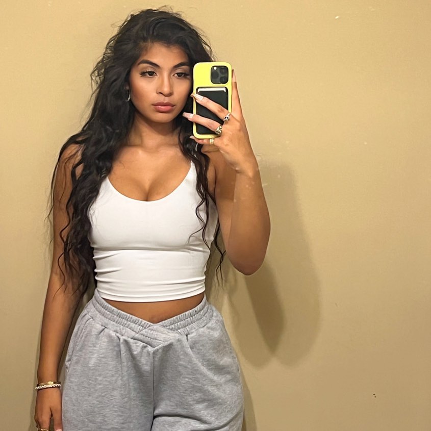 Brittany Boltinhouse, ex-Miss North Carolina USA, holds a yellow phone and wears a white top and gray sweatpants in mirror selfie