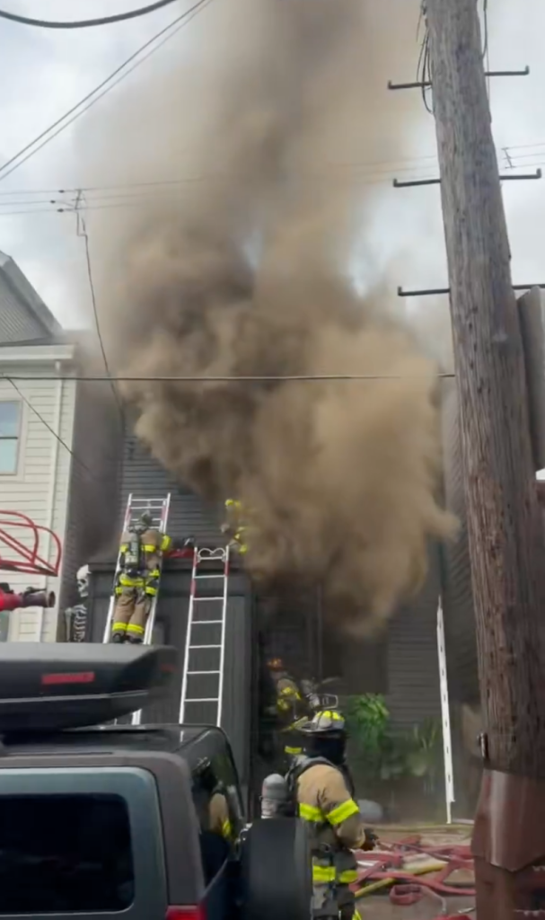 Firefighters battle a blaze at Tom Savini's home, with thick smoke billowing from the building.