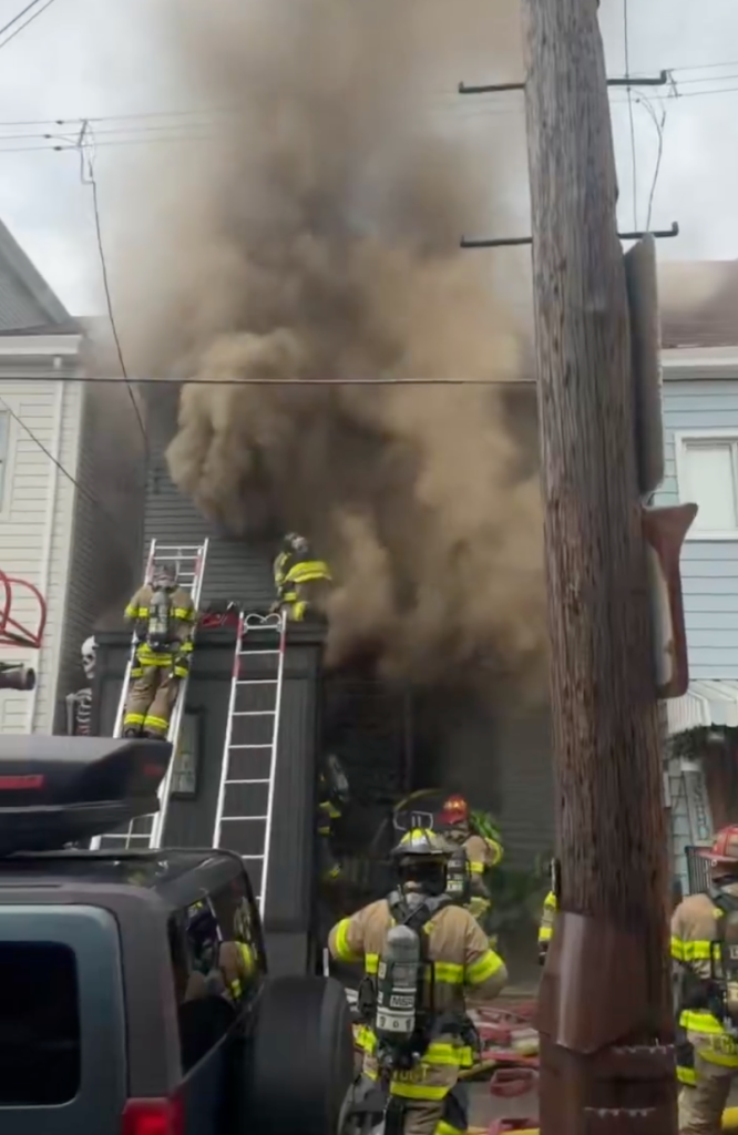 Firefighters battling a blaze at a home, with thick smoke billowing from the structure.