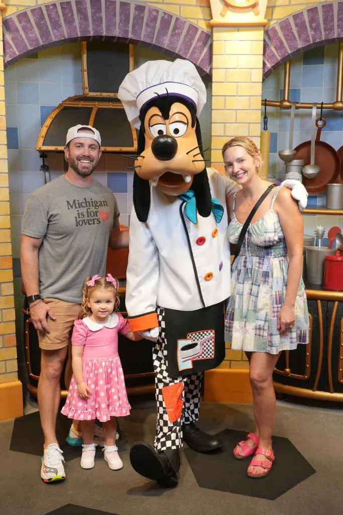 A family posing with Goofy in a chef's costume.
