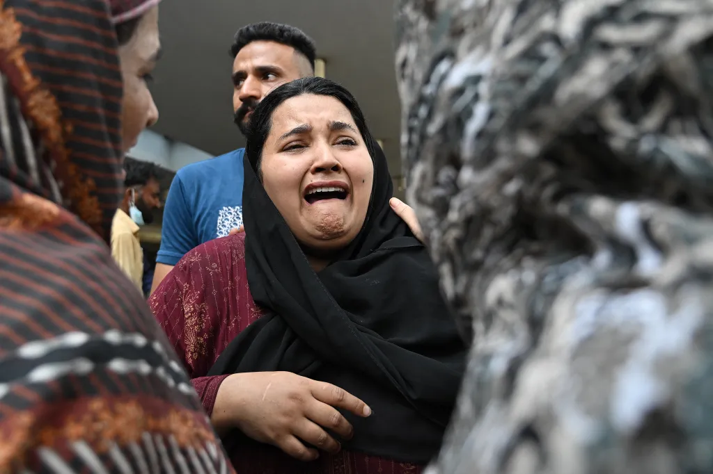 A woman cries in despair, supported by a man and another person, after losing her child in a hospital fire in Islamabad.