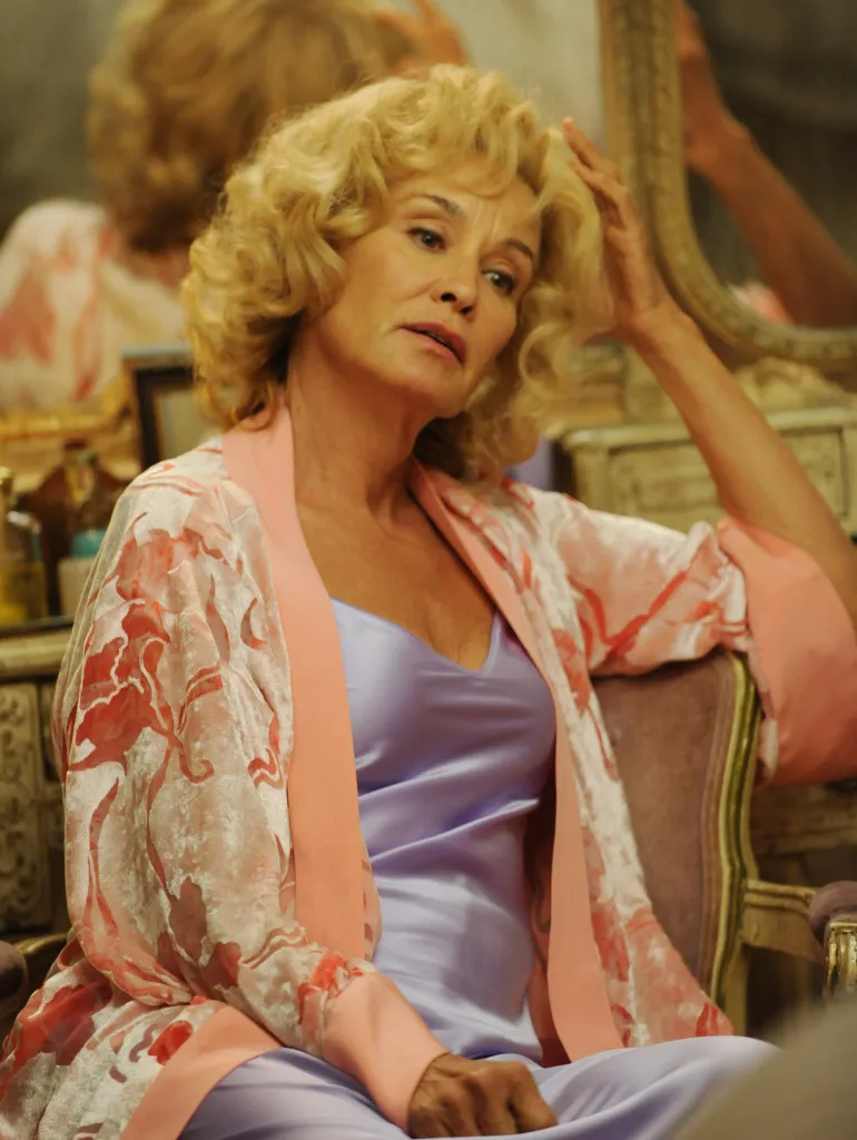 Jessica Lange in a pink robe and purple nightgown in 