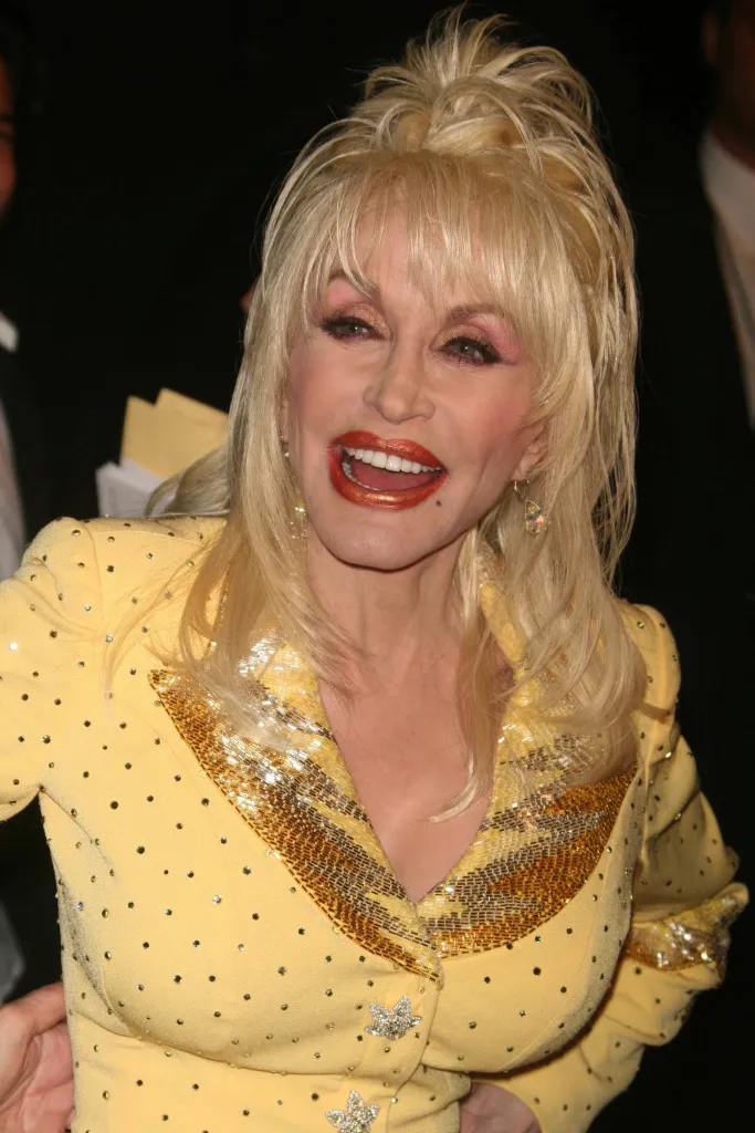 Dolly Parton smiling in a yellow embellished top.