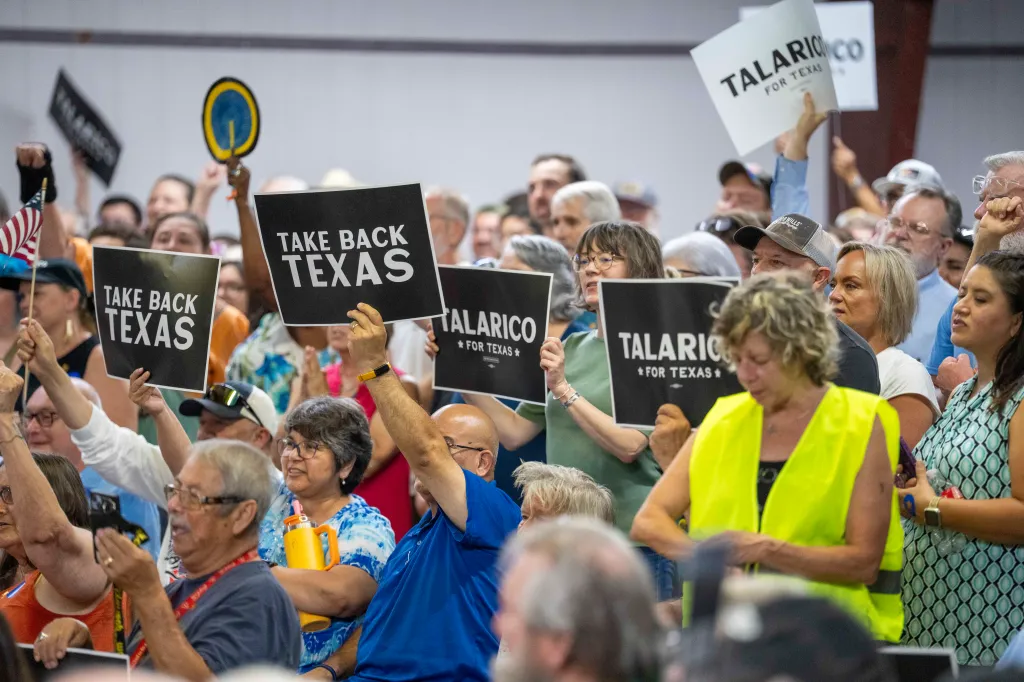 Supporters at a James Talarico campaign rally in Lockhart, Texas, hold up signs that read 