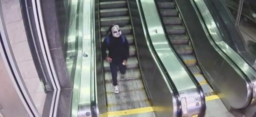 Zymire Hughes running up an escalator while wearing a mask.