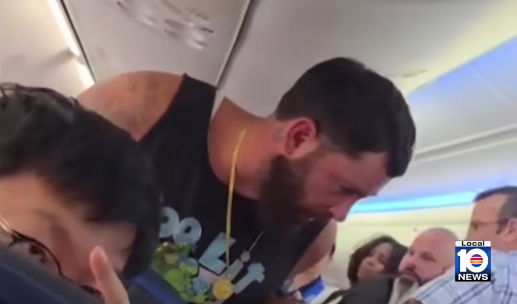 Man on a plane bending over to comfort a woman.