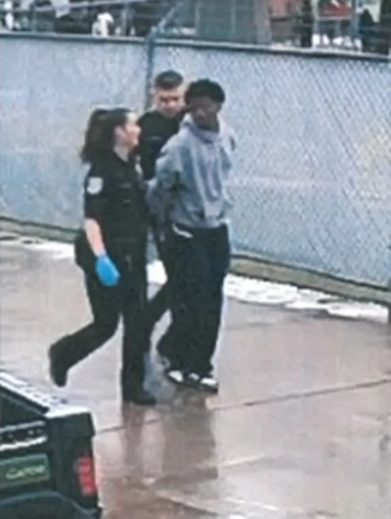 Karmelo Anthony in handcuffs, escorted by two police officers.