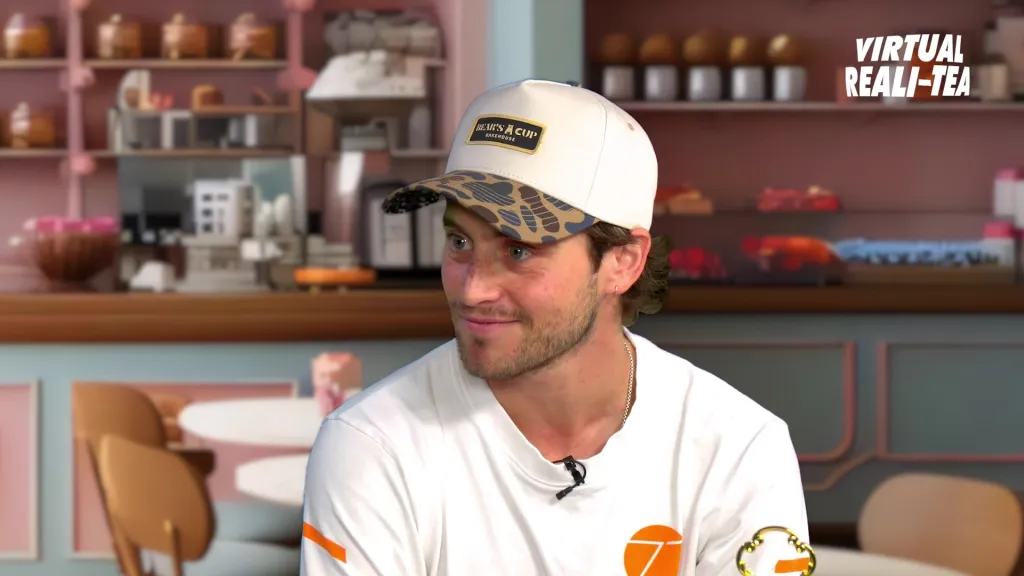 Liam Obergfoll wearing a baseball cap with a camouflage brim, smiling and looking to his left.