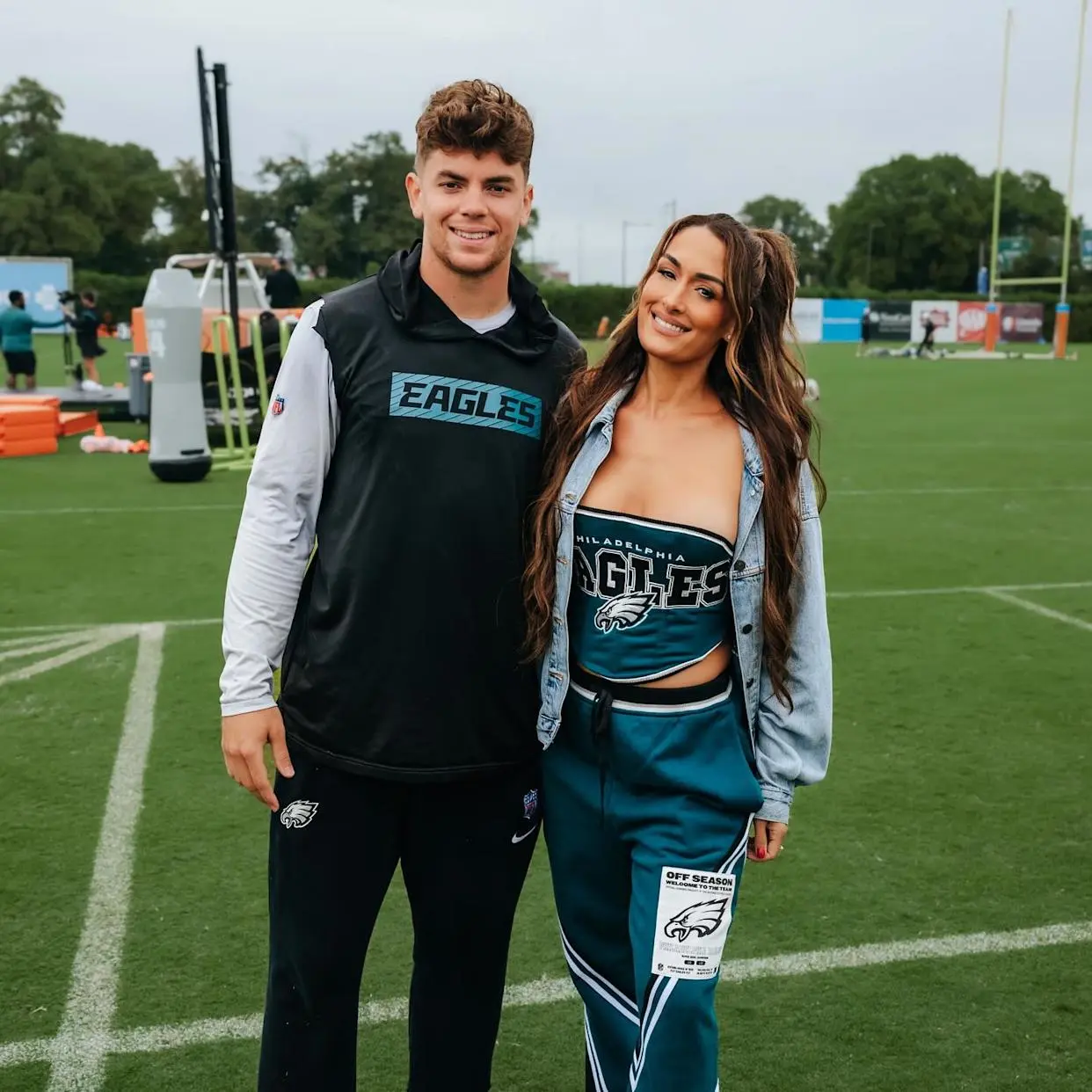 Nikki Bella and Cooper Dejean posing together on a football field.