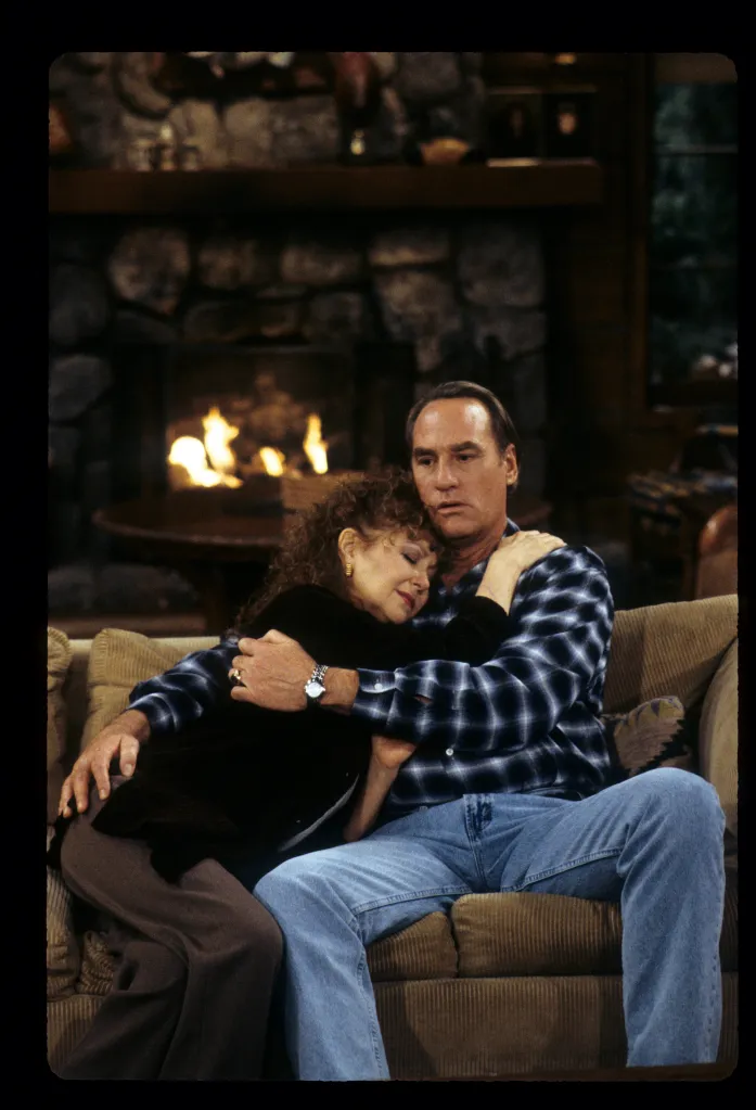 Shelley Fabares and Craig T. Nelson embracing on a couch in front of a fireplace.